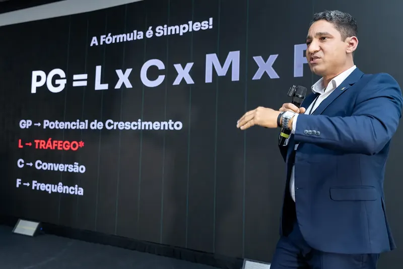 Lúcio Artes no palco, explicando uma fórmula no telão